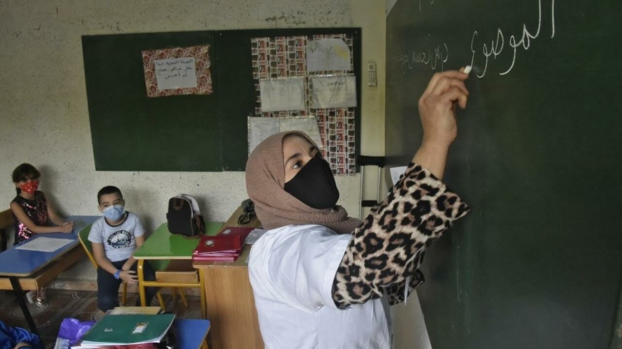 A teacher addresses pupils while wearing a face mask due to the COVID-19 pandemic on the first day of school following the resumption of classes in the Algerian capital Algiers on October 21, 2020. (Photo by RYAD KRAMDI / AFP)