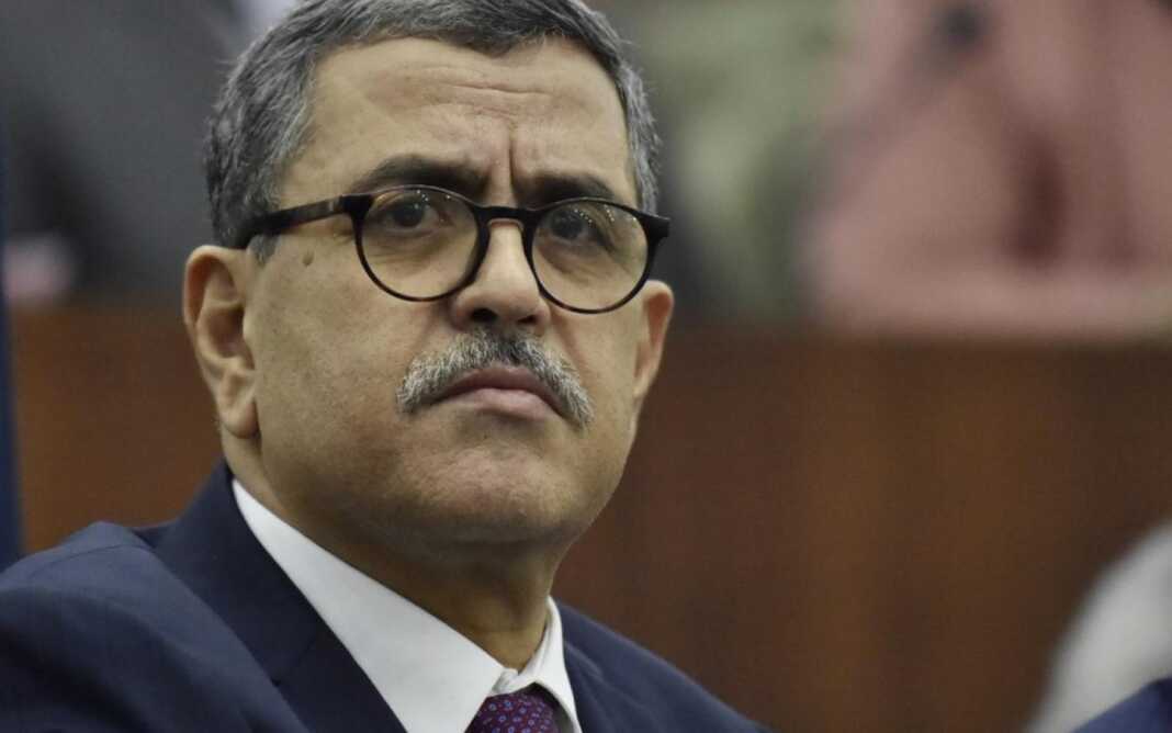 Démission du gouvernement Djerad Homme sérieux portant lunettes dans un environnement professionnel.