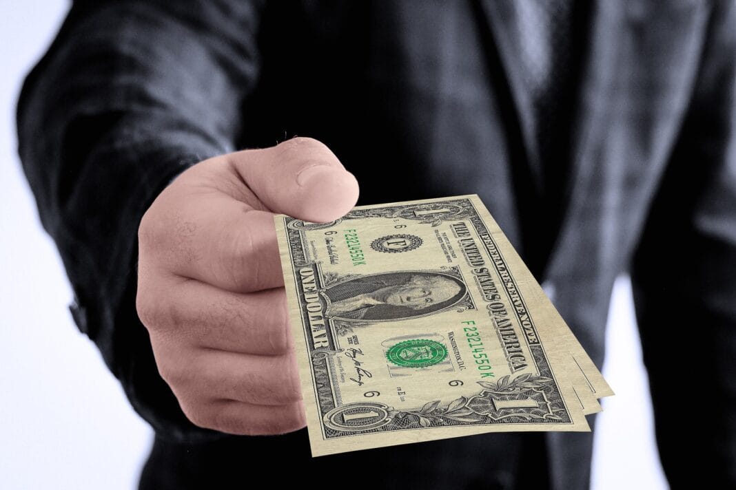 Main tenant des billets de dollar, symbole de corruption.