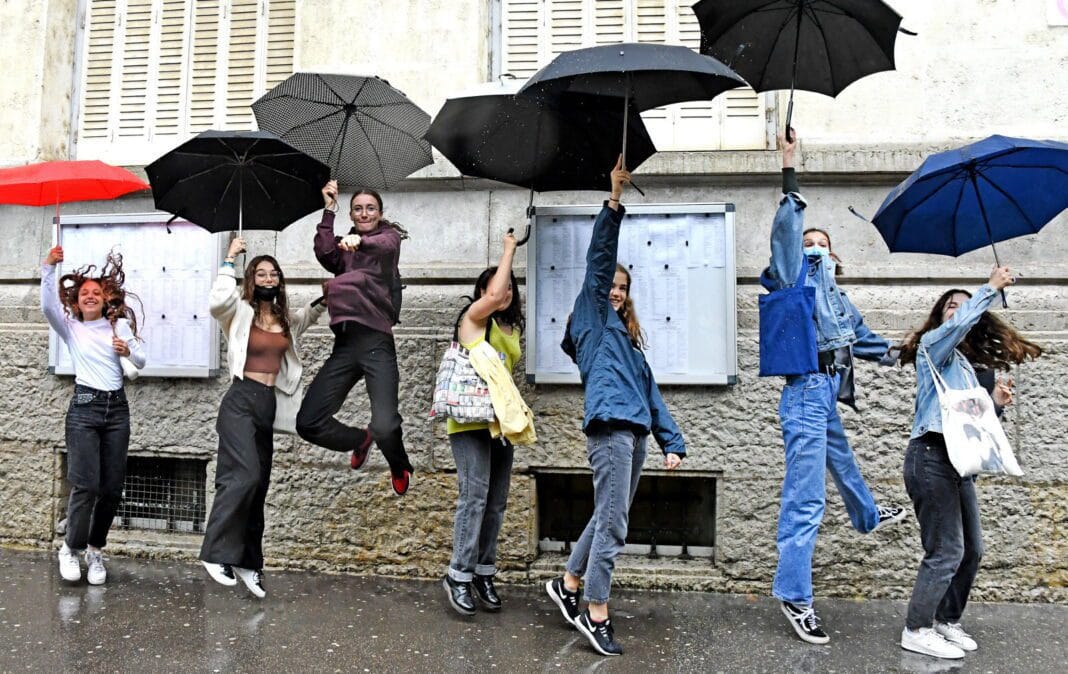 BAC 2021 en Algérie : les moyennes d’admission universitaire par filière Groupe de jeunes avec parapluies colorés sous la pluie à l'extérieur.