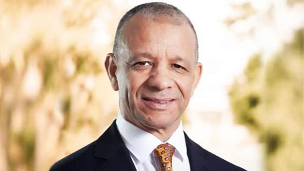 Homme d'affaires souriant en costume dans un environnement extérieur.
