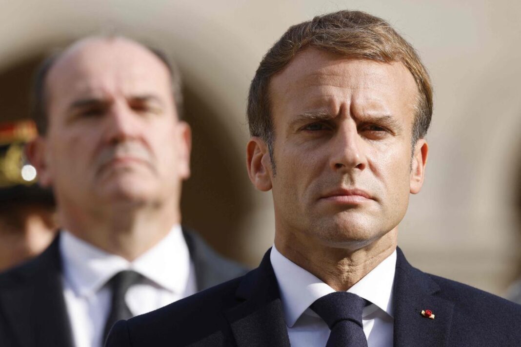 Algérie-France : Quand Macron bousculait les codes… Emmanuel Macron en cérémonie officielle, visage sérieux, en arrière-plan un autre homme.