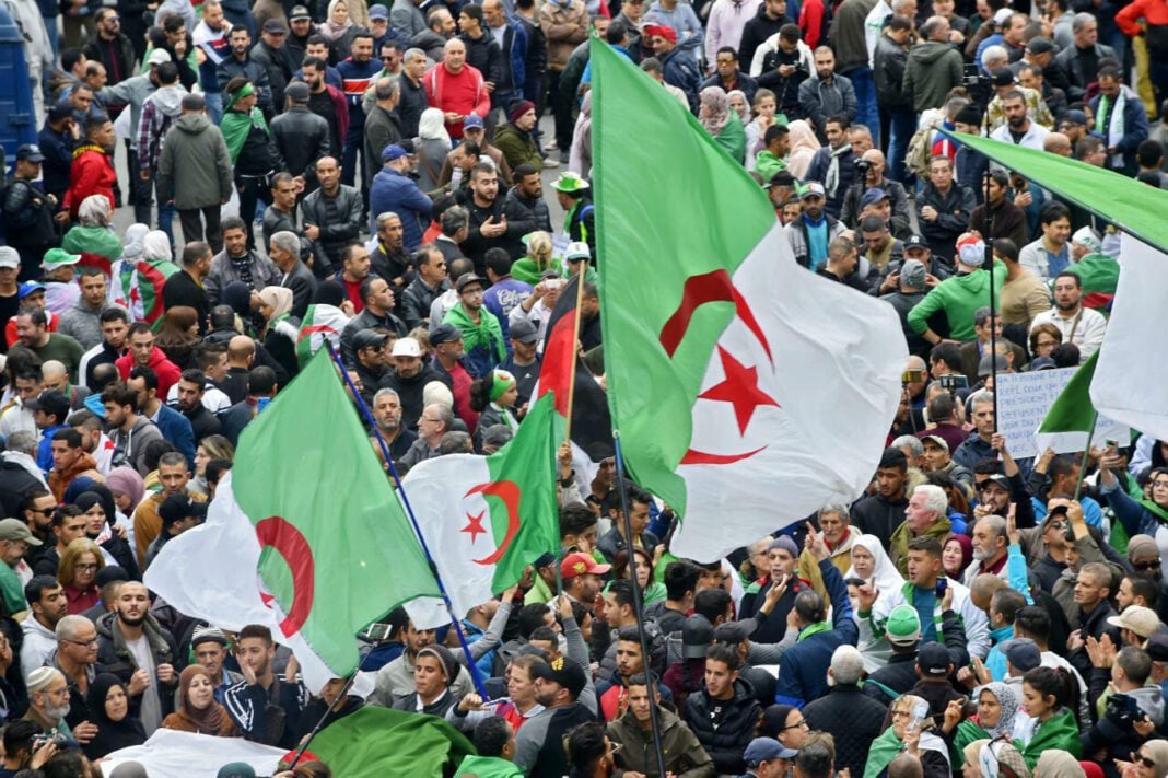 Hirak : Des personnalités proposent un débat public Grande foule en Algérie avec drapeaux algériens et pancartes.