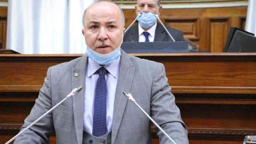 Homme politique en séance parlementaire portant un masque.