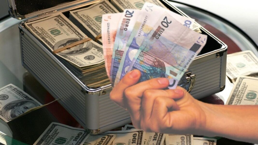 Argent et devises dans une mallette Main tenant des billets de banque en euros dans une mallette en métal.