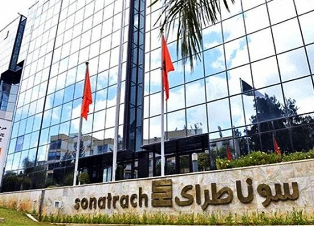 Affaire Sonatrach 1 : le procès reporté à la prochaine session Bâtiment moderne de Sonatrach avec drapeaux rouges et façade en verre.
