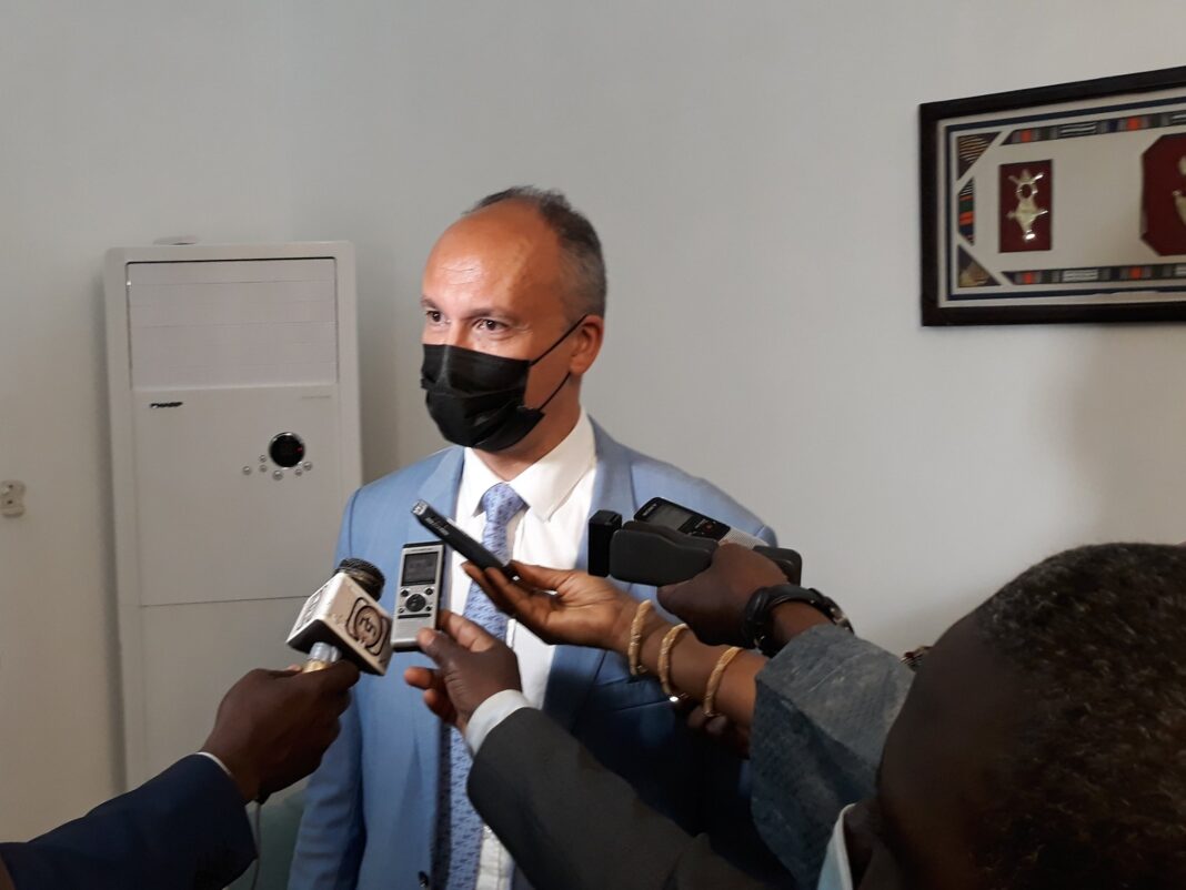 Responsable politique en interview, portant un masque noir, répondant aux questions des médias.
