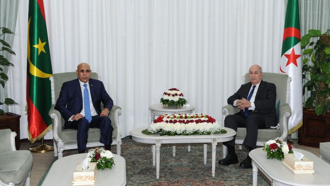 Route Tindouf-Zouerat : Tebboune souligne l’impératif d’entamer les travaux Deux hommes en costume assis dans une salle de réunion officielle en Algérie.