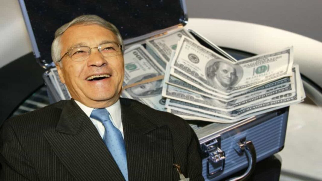 Homme d'affaires souriant avec des dollars et un ordinateur portable.