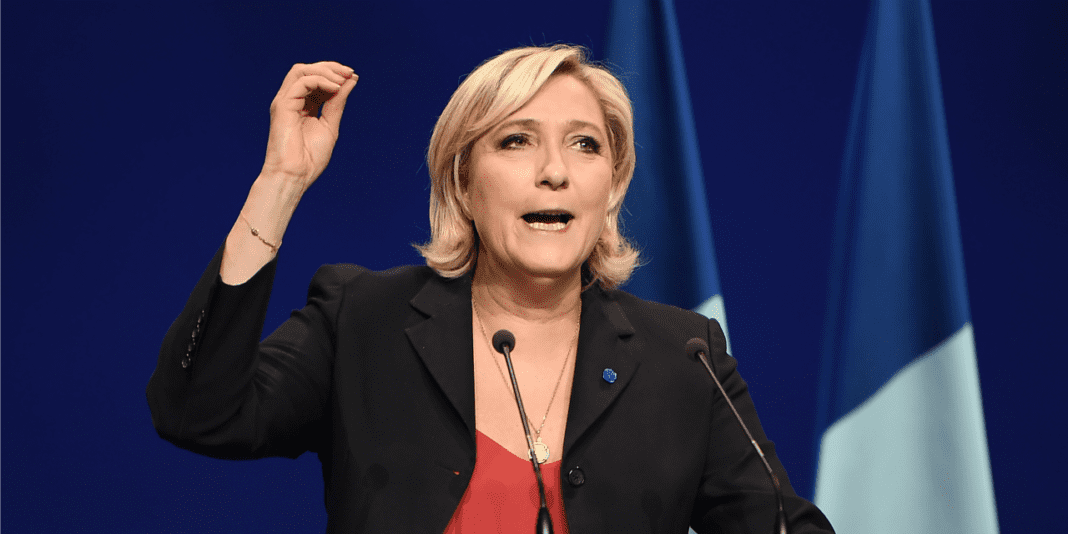Marine Le Pen accusée d’avoir détourné 600 000 euros Premier ministre Élisabeth Borne en discours avec drapeau français en arrière-plan.