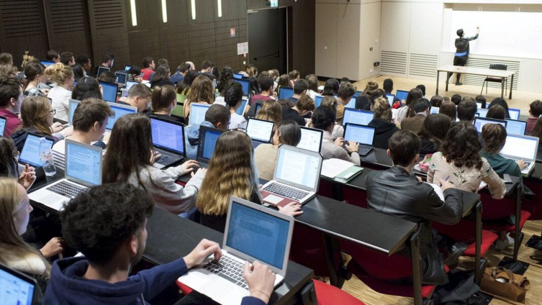 Étudiants en conférence avec ordinateurs portables en salle de classe.