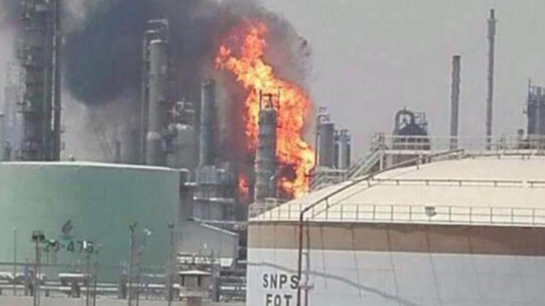 Fumée noire et flammes dans une usine industrielle en feu.
