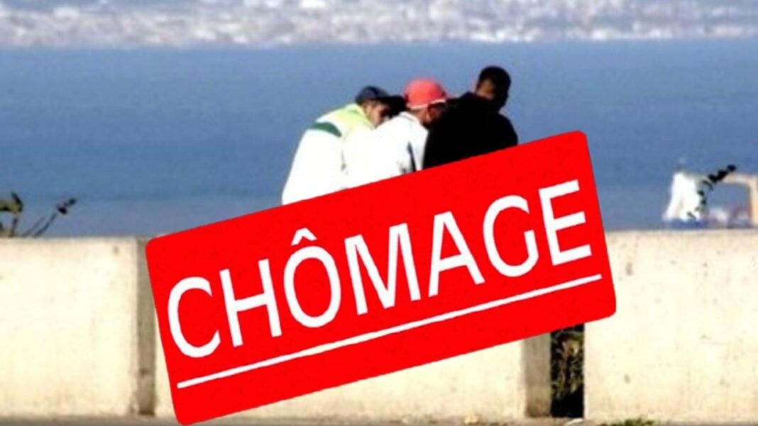 Groupe de personnes discutant près de la mer avec panneau chômage.