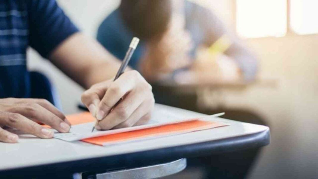 Étudiant prenant des notes en classe Étudiant écrivant sur un cahier dans une salle de classe lumineuse.