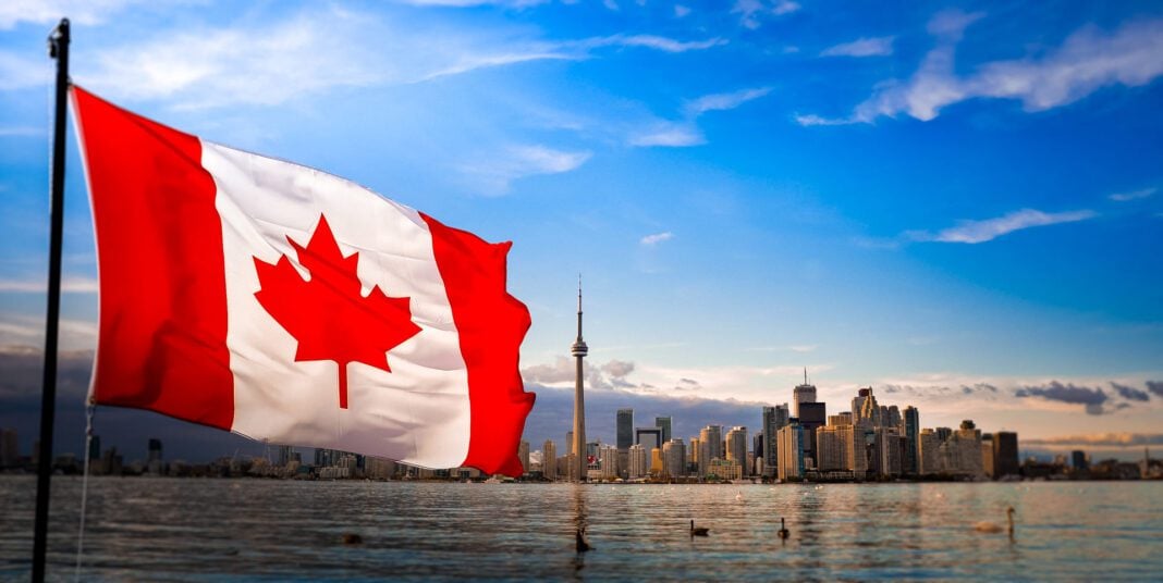 Canada : Le consulat d’Algérie au cœur d’un scandale Drapeau du Canada flottant avec la skyline de Toronto en arrière-plan.
