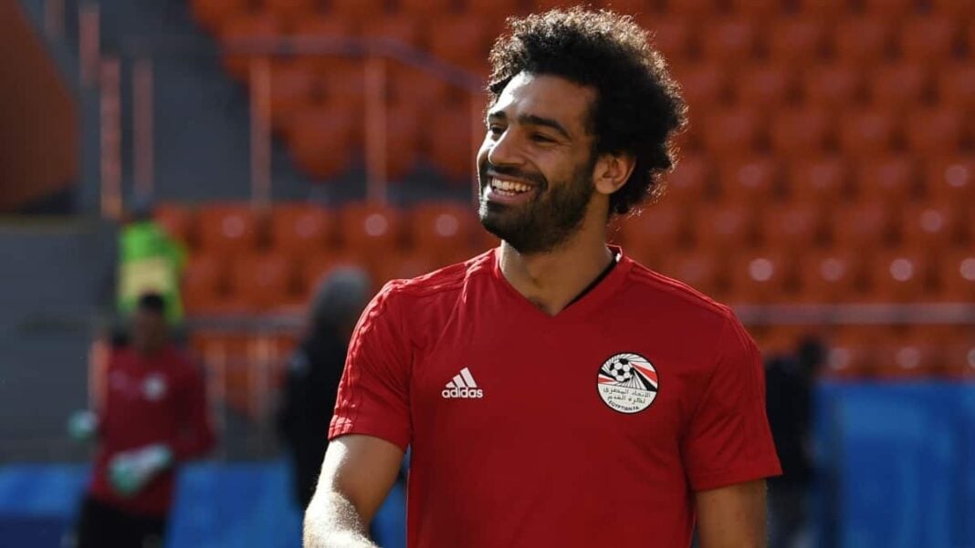 Footballeur africain souriant en stade Footballeur africain portant maillot rouge dans un stade vide.