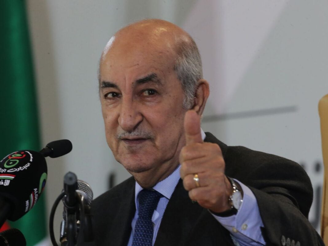 Homme politique donnant un signe de thumbs-up lors d'une conférence.