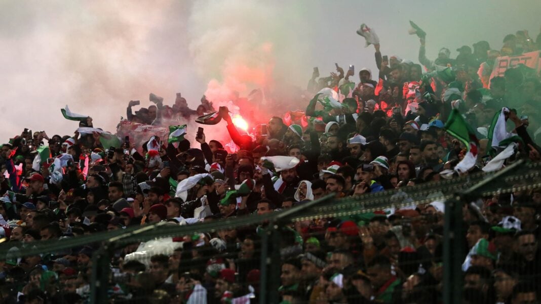 Supporters algériens avec drapeaux et fumigènes lors du match.