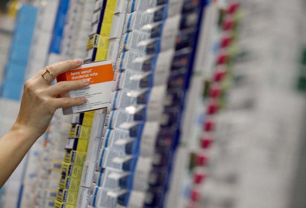Main tenant une boîte de médicament dans une pharmacie.
