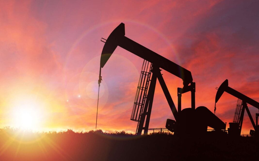 2 gisements de combustibles découverts en Algérie Puits de pétrole au coucher du soleil, silhouette contre ciel orange.