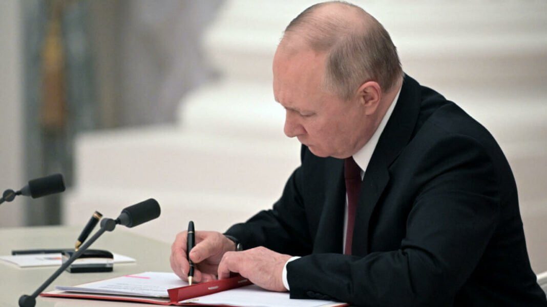 Vladimir Poutine signe un document officiel lors d'une réunion.