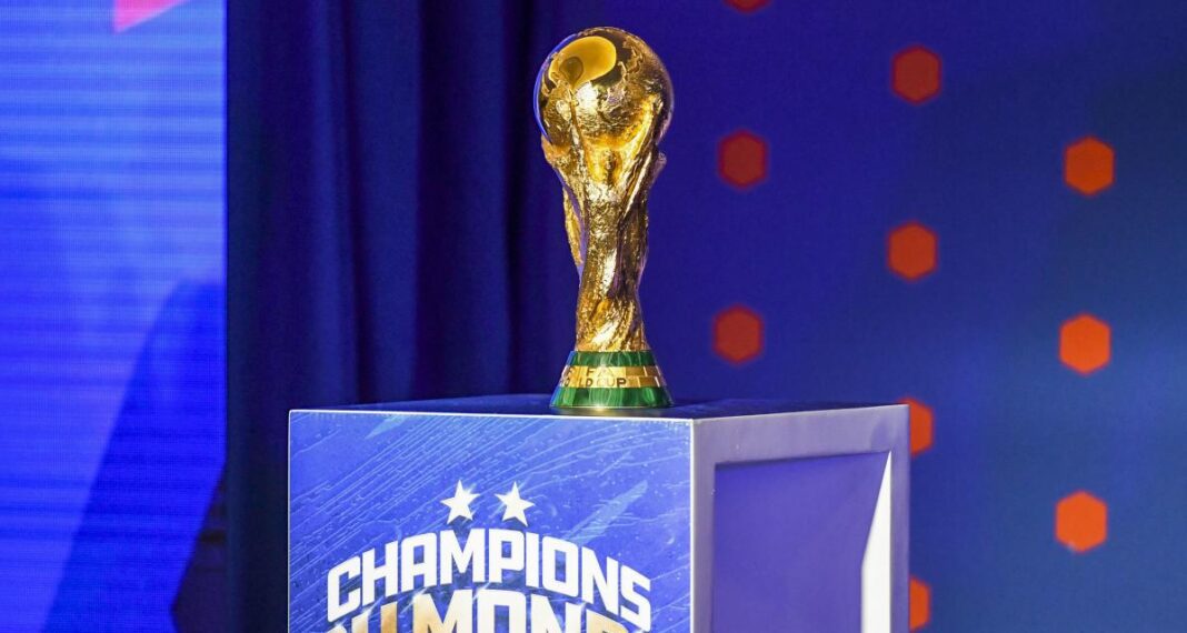 Trophée de la Coupe du Monde de football sur un podium bleu.
