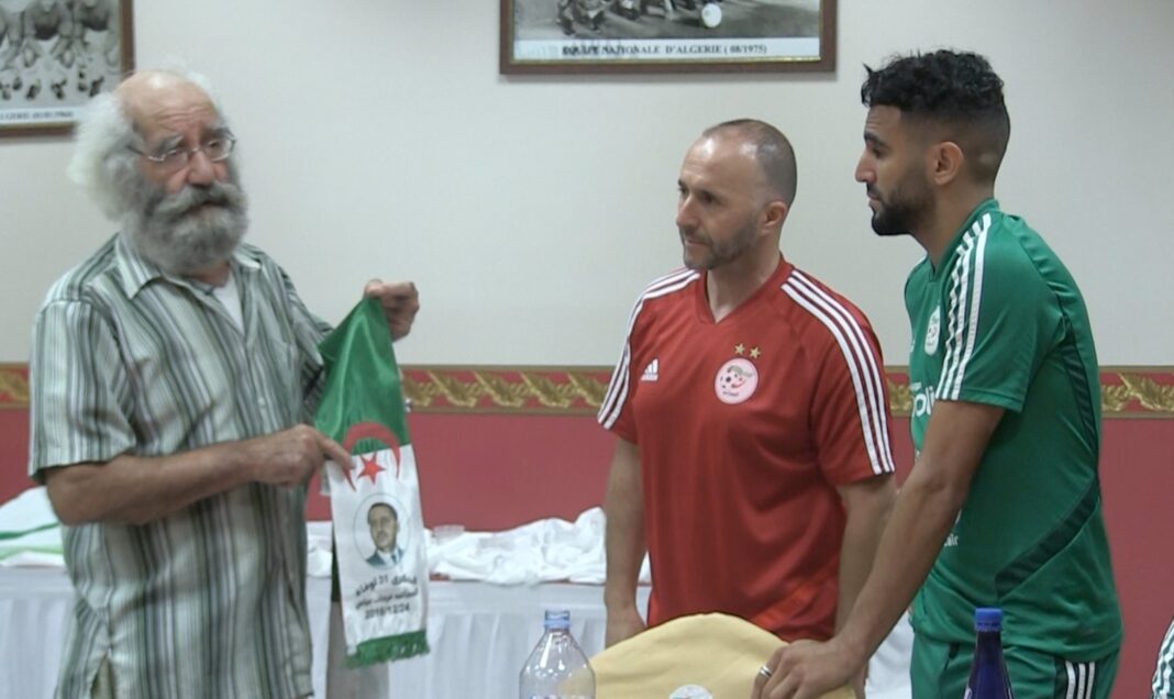 Trois hommes discutent lors d'une rencontre sportive en Algérie.