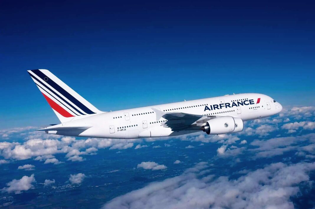 Avion Air France survolant les nuages dans un ciel bleu clair.