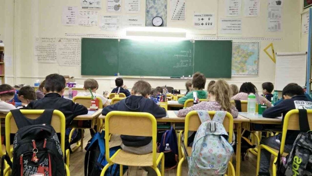 Enfants en classe primaire avec tableau noir et matériel scolaire.