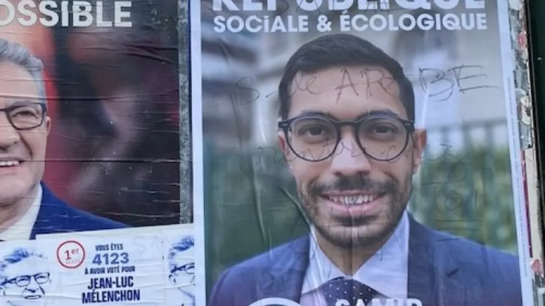 « Sale Arabe, rentre chez toi » Une expression raciste à l’encontre de ce candidat en France Portrait d'un candidat politique avec lunettes et costume bleu.