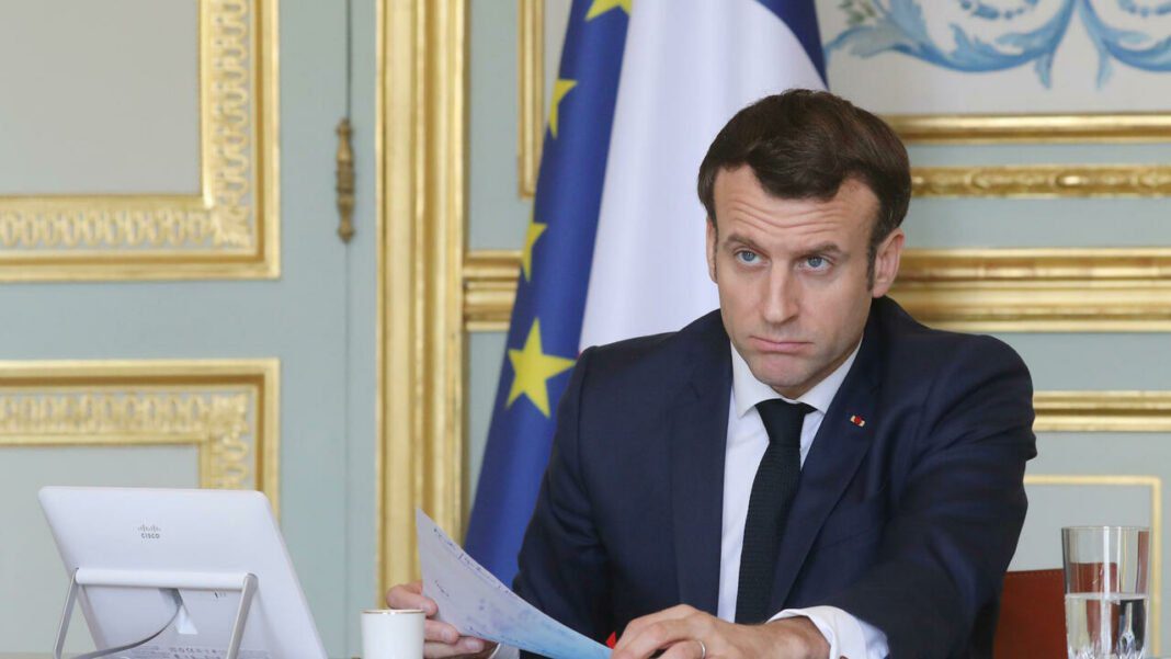 France: Macron vient de nommer un nouveau Premier ministre Emmanuel Macron en réunion, portant un costume sombre, avec drapeau français et européen en arrière.