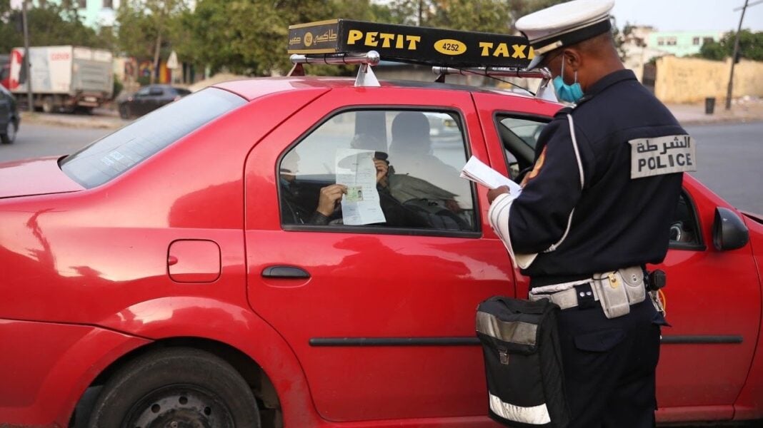 Contrôle de taxi par la police au Maroc Policier vérifiant un taxi dans une rue marocaine.