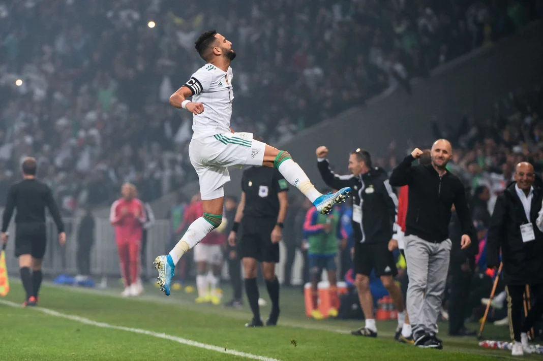 Joueur d'Algérie célébrant une victoire sur le terrain de football.