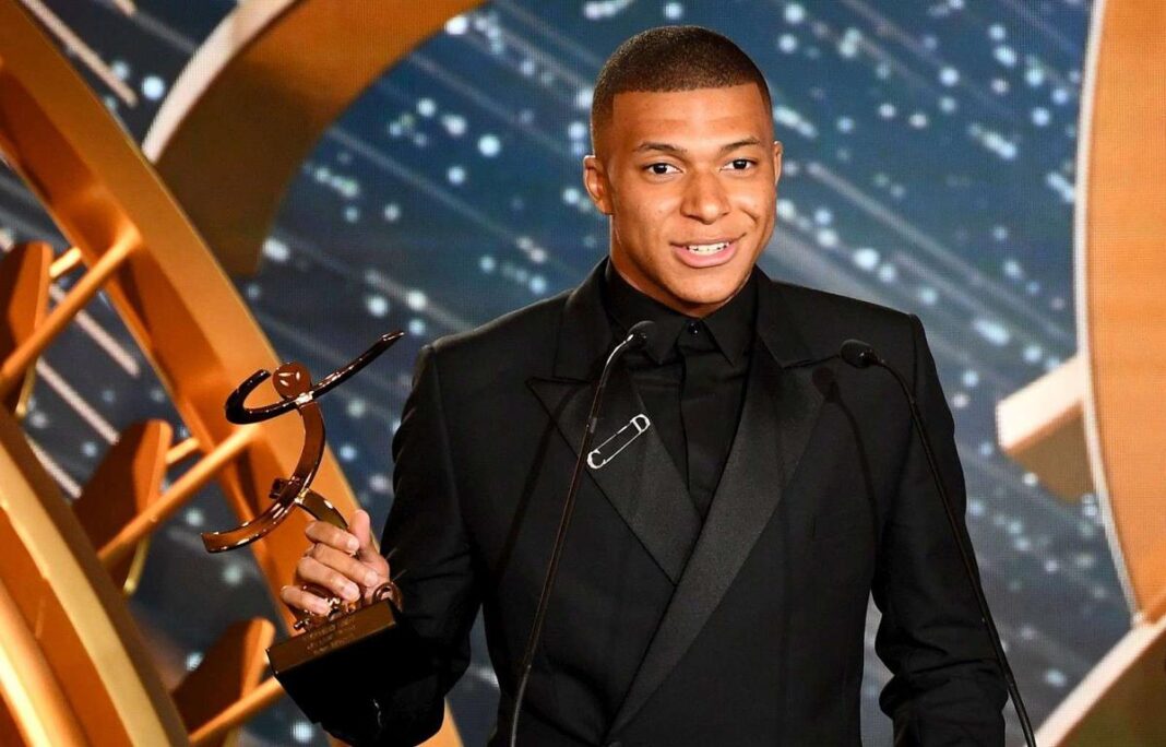 Kylian Mbappé avec un trophée lors d'une cérémonie de remise de prix.