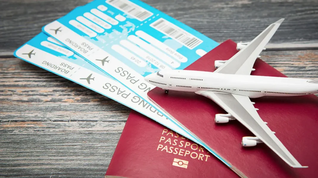 La guerre en Ukraine a changé les destinations des Algériens vivant à l’étranger Billets d'avion, passeport et modèle d'avion sur une table en bois.