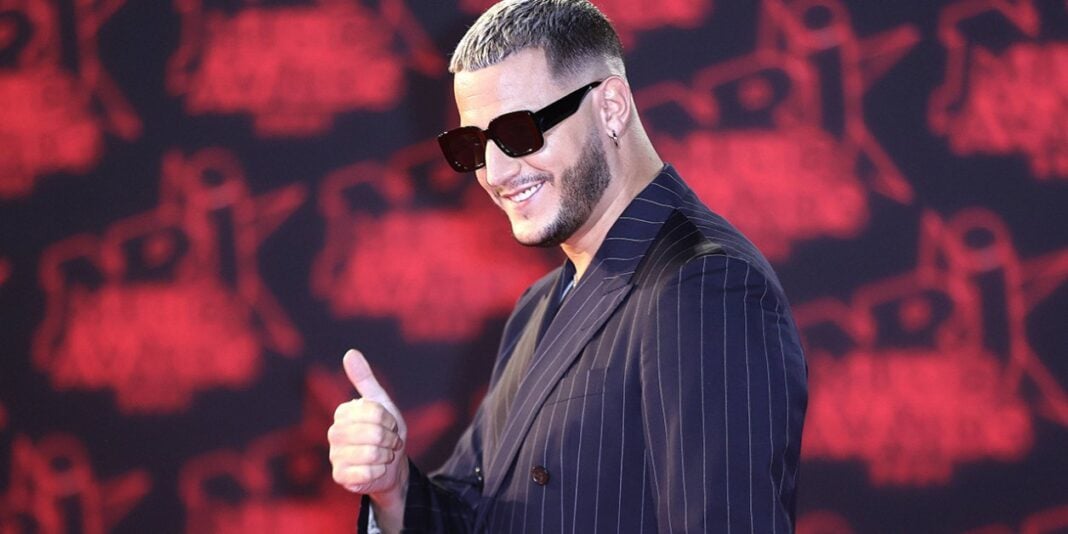 Origines de DJ Snake star planétaire DJ Snake portant des lunettes de soleil, souriant lors d'un concert.