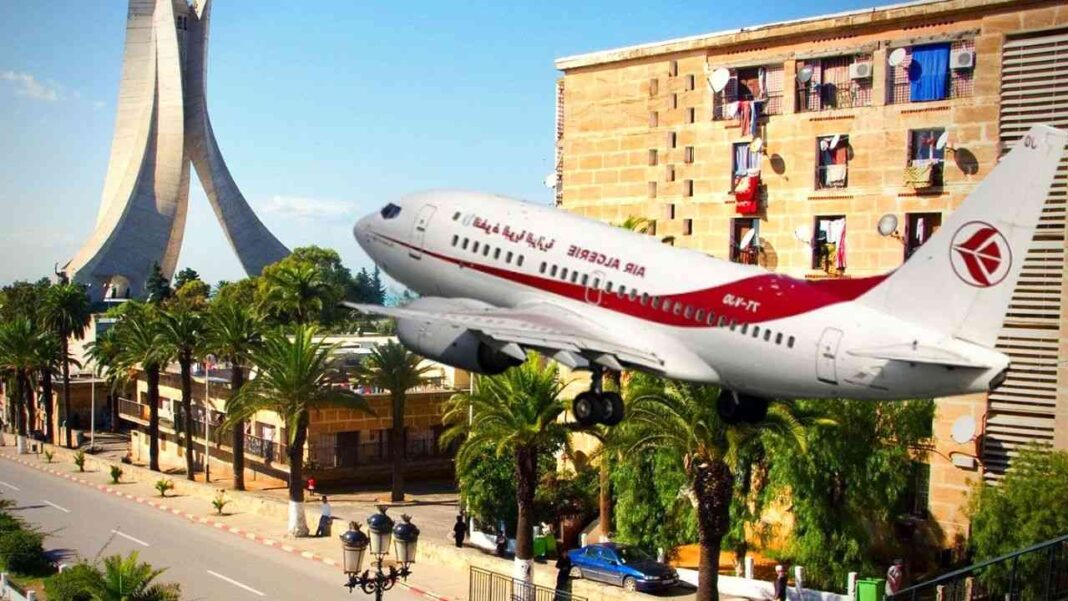 L’Autriche veut l’ouverture de vols directs avec l’Algérie Avion d'Air Algérie survole une ville avec des bâtiments et des palmiers.