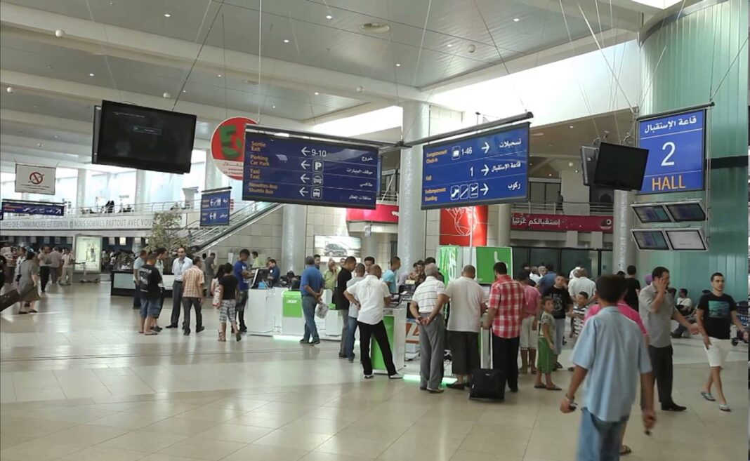 Voyage : Une saisie incroyable sur les femmes. Passagers à l'aéroport d'Alger avec panneaux d'information.