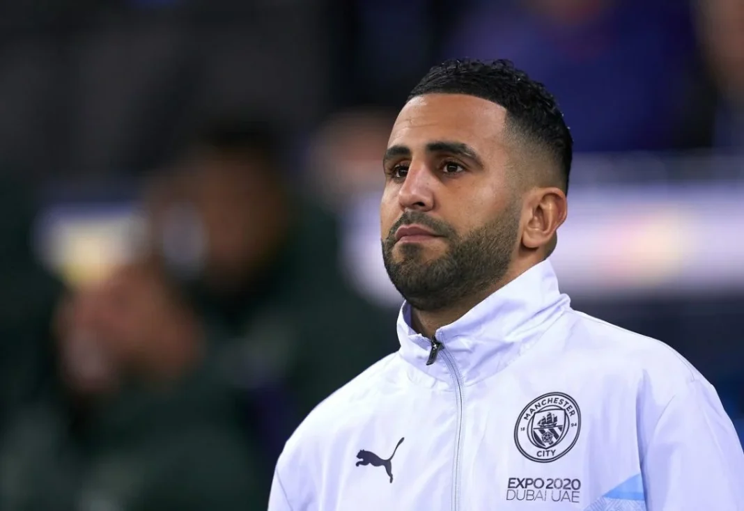 Mahrez reçoit un cadeau pour sa fille Mahrez lors d'un match, portant un maillot de Manchester City.