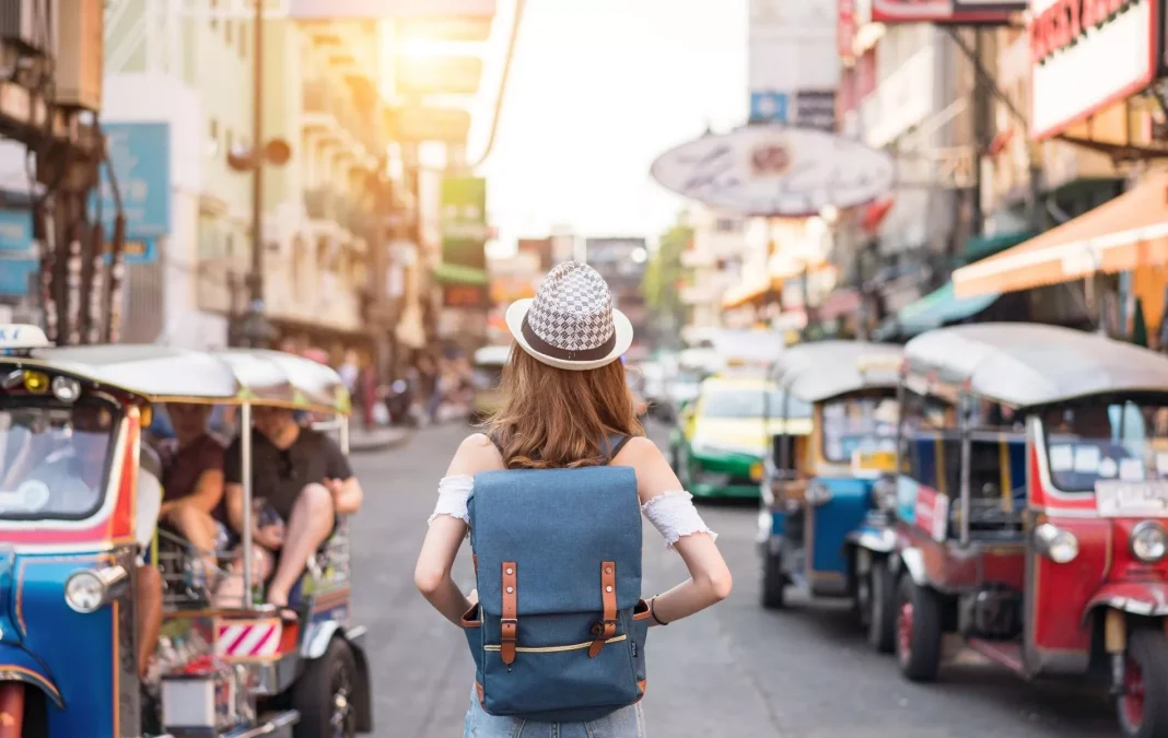 Voyageur féminin dans une rue animée Femme avec sac à dos dans une rue bondée de tuk-tuks et boutiques.