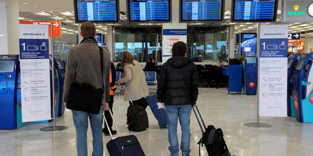 Passagers à l'aéroport de Paris avec valises, affichages de vols perturbés.