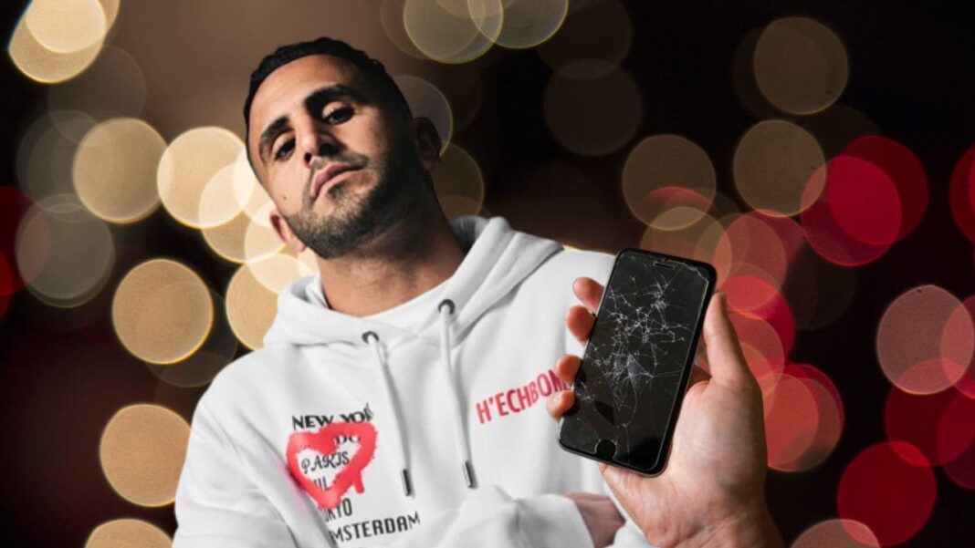 Riyad Mahrez et le téléphone cassé Riyad Mahrez tenant un téléphone cassé, expression sérieuse.