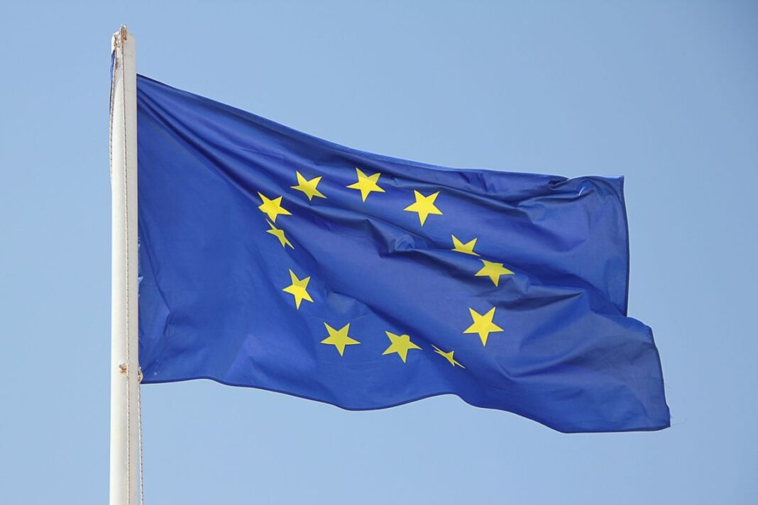 Urgent ! Les Algériens leaders des nationalités citées de quitter le territoire de l’UE Drapeau de l'Union européenne flottant dans le ciel bleu clair.