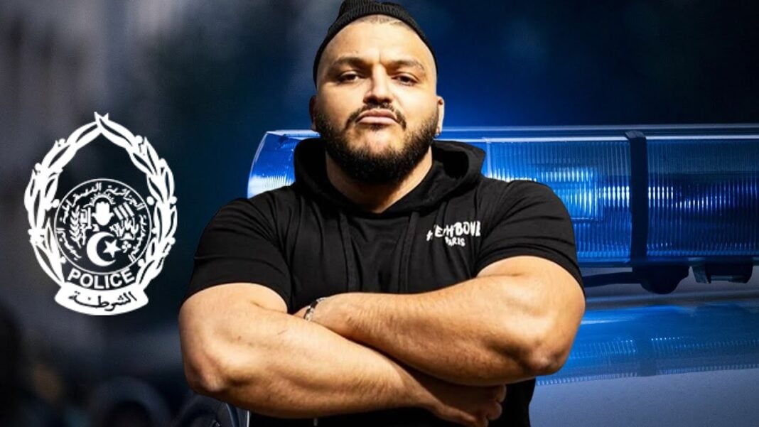 Le rappeur Trap King retrouve la liberté Rappeur Trap King avec bras croisés devant une voiture de police.