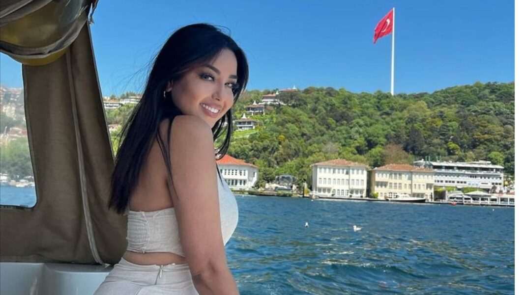 Le coup de gueule de Yasmine Belkacem Yasmine Belkacem souriante en bateau avec vue sur la mer et la ville.