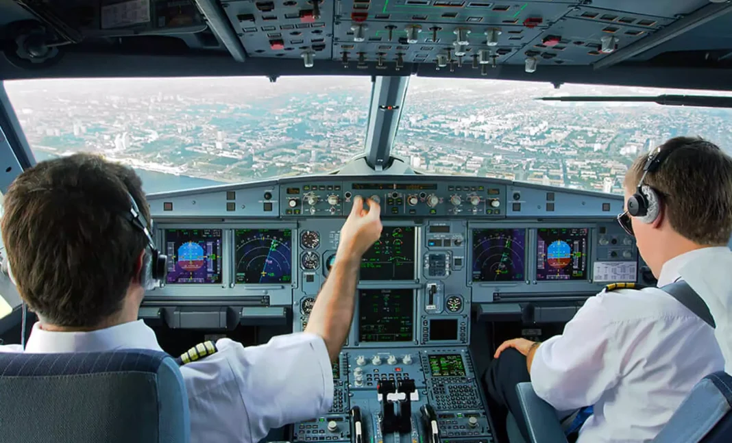 Les pilotes d’Air Algérie menacent d’aller en Grève Deux pilotes dans le cockpit d'un avion avec vue sur la ville en arrière-plan.