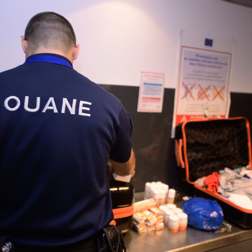 Agent des douanes en contrôle Agent des douanes inspectant des produits saisis à la frontière.