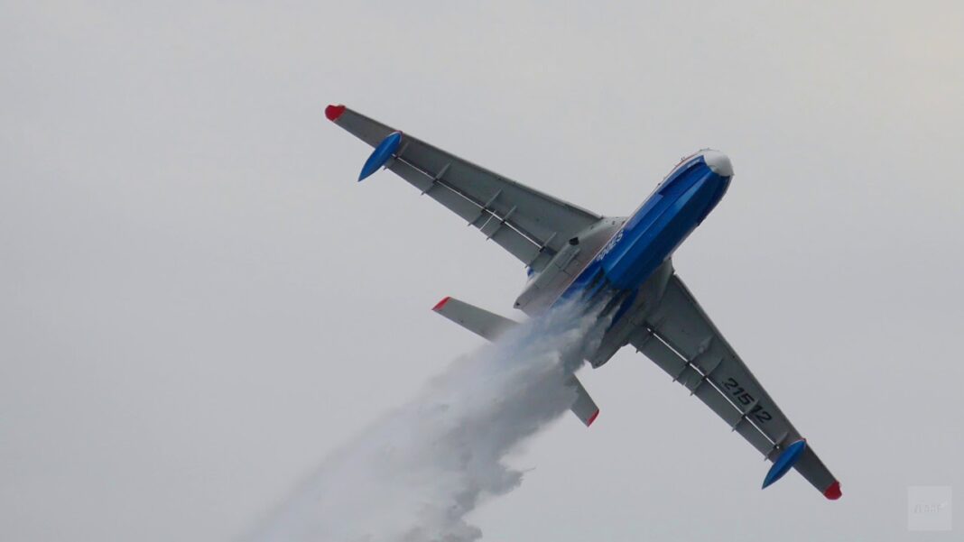 Avion Beriev B-200 en vol, déversant de l'eau contre un incendie.