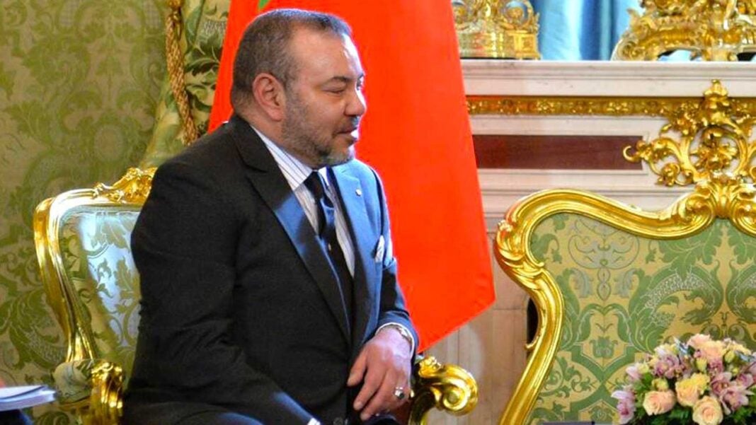 Homme politique lors d'une rencontre officielle Homme politique en réunion officielle avec décor luxueux et drapeau marocain en arrière-plan.