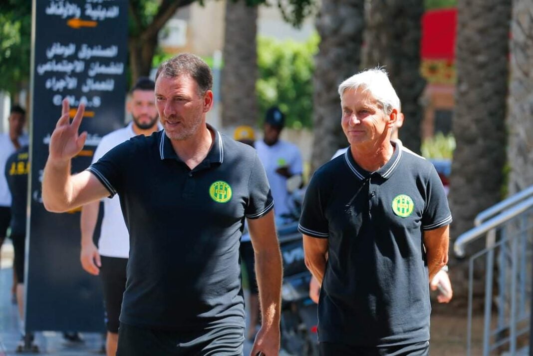 Ligue 1 algérienne : la JSK n’y arrive plus, l’entraîneur limogé Deux entraîneurs de football en conversation lors d'un événement sportif.